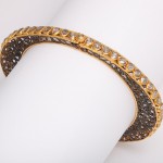 A gold and diamond bracelet is shown on top of a white background.