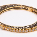 A gold and diamond bangle bracelet with intricate design.