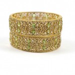 A pair of gold bangles with green stones.