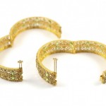 A pair of gold and green earrings on a white background