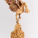 A gold bird with wings and a pink stone on its head.