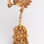 A gold and ruby pendant with a bird on it.