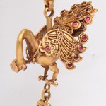 A gold and ruby peacock necklace with a chain.