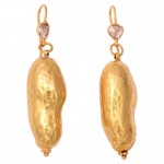 A pair of gold earrings with a large peanut shaped piece.