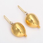 A pair of gold earrings with a large ball on them.