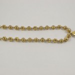 A gold chain with a large bead and a small bead.