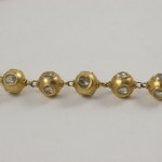 A gold chain with large balls and small diamonds.
