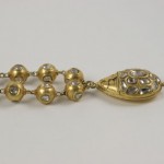 A gold necklace with a ladybug pendant and six beads.