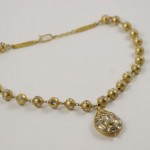 A gold necklace with a small pendant on it.