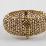 A gold bracelet with white stones on it