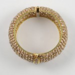A gold bracelet with three rows of diamonds.