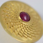 A gold ring with a red stone on top of it.