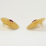 A pair of gold earrings with red stones.
