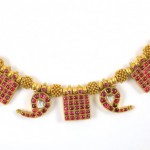 A necklace with red stones and gold letters.