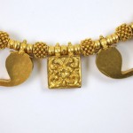 A gold necklace with some decorative metal pieces.