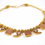 A necklace with red stones and gold plated shapes.