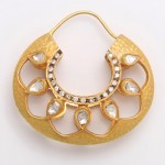 A gold hoop earring with clear stones on it.