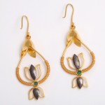 A pair of earrings with gold and green stones.
