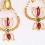 A pair of gold earrings with red and green stones.