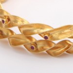 A close up of the gold chain with red stones