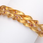 A gold bracelet with rubies on it.