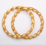 A pair of gold bracelets on top of each other.