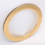 A gold bangle with black diamonds on it.