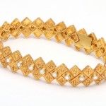A gold bracelet with pearls on it.