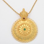 A gold necklace with a green stone on it.