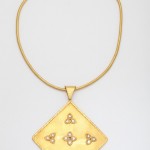 A gold necklace with four triangles and three small diamonds.
