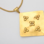 A gold necklace with five flowers on it.