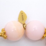 A close up of the pink beads on a gold necklace