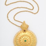 A gold necklace with a round pendant on it.
