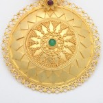 A gold medallion with a green stone on it.
