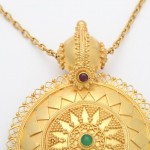 A gold necklace with a large pendant on it