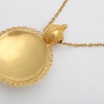 A gold necklace with a round pendant on it.