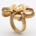 A gold ring with a flower shaped diamond center.
