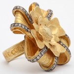 A gold ring with a flower and diamond center.