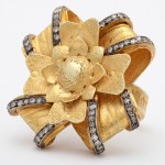 A gold and diamond flower ring with black diamonds.
