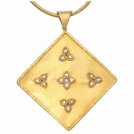 A gold and diamond pendant with four triangles.
